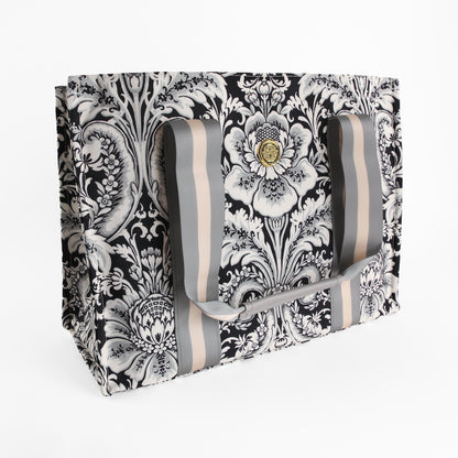 Introducing the Damask Noire Tote Bag—a black and white damask canvas tote adorned with a floral pattern and finished with wide gray and beige striped handles. Pictured against a white background, this elegant bag makes the perfect gift for women who appreciate a sophisticated, stylish market tote.