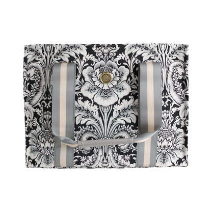 The Damask Noire Tote Bag features an ornate black and white floral damask pattern on a rectangular silhouette, complemented by vertical gray and cream straps and a central gold decorative button.