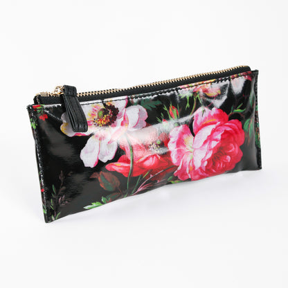 Introducing the Noire Pencil Case—a rectangular, black zippered pouch crafted from glossy laminated cotton and adorned with a floral print featuring pink and white flowers. Perfect as a stylish zippered pencil case or a chic desk accessory gift.
