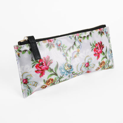 Phoebe Pencil Case – a rectangular, durable laminated cotton pencil case with a zipper and black strap, featuring a multicolored floral pattern on a light background and photographed on a white surface.