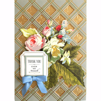 An Anna Griffin thank you card adorned with a blue ribbon and delicate flowers.