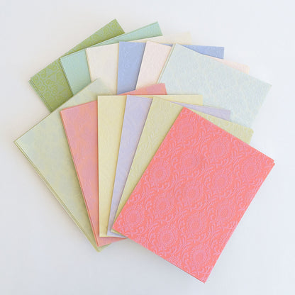 A fanned display of Fancy Flocked Card Layers in textured pastel shades—pink, green, blue, and cream—with elegant decorative patterns, ideal for refined craft projects.