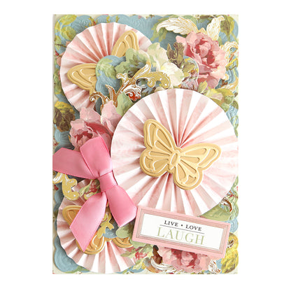 Decorative greeting card showcasing pink rosettes, gold butterfly accents, a pink bow, and a floral background enhanced with floral rub on transfers from the Ultimate Francesca Papercrafting Collection with Rub Ons. Features a tag that reads “Live Love Laugh,” making it an elegant addition to your scrapbook supplies.