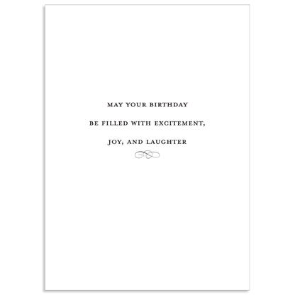 The Francesca Happy Birthday Card is a white card featuring black text with a touch of gold foil, reading "May your birthday be filled with excitement, joy, and laughter," along with a small decorative design.