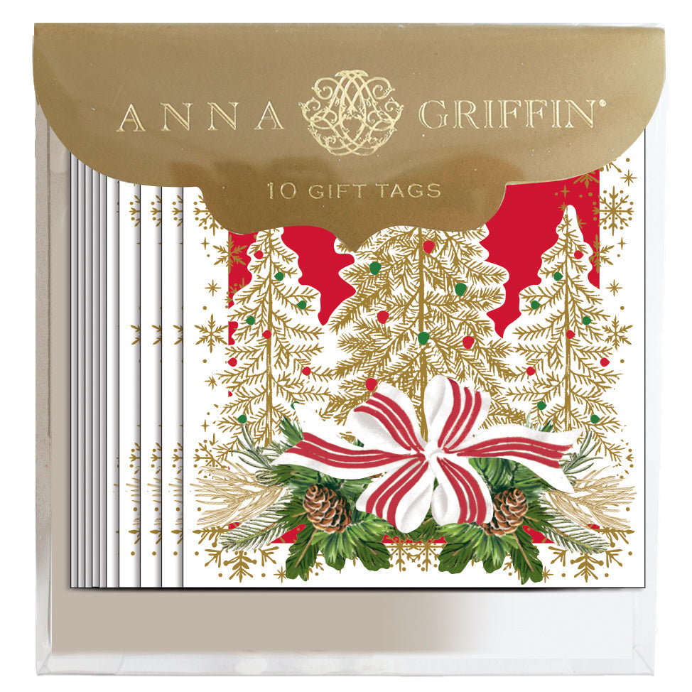 A box labeled "Three Trees Tag 10 ct" by Anna Griffin containing Christmas gift tags that depict white trees, with red and gold accents, pinecones, and a large red and white bow.