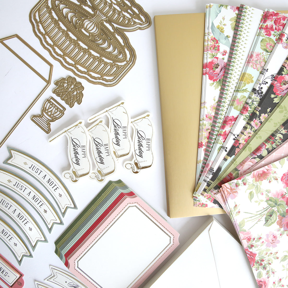 A variety of paper and card items, including interactive cards and Anna Griffin's Garden Fountain Easel Finishing School Kit, are laid out on a table.