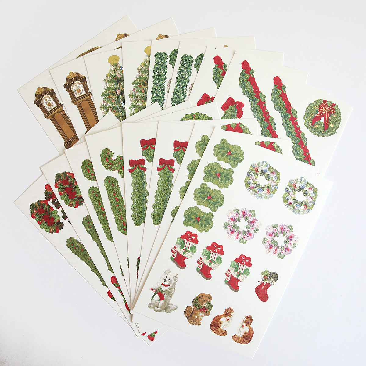 Ten Garland Staircase Die Cut Sticker sheets, arranged in a fan shape, feature wreaths, garlands, stockings, clocks, bows, a dog, and rabbits—perfect festive embellishments for scrapbooks.