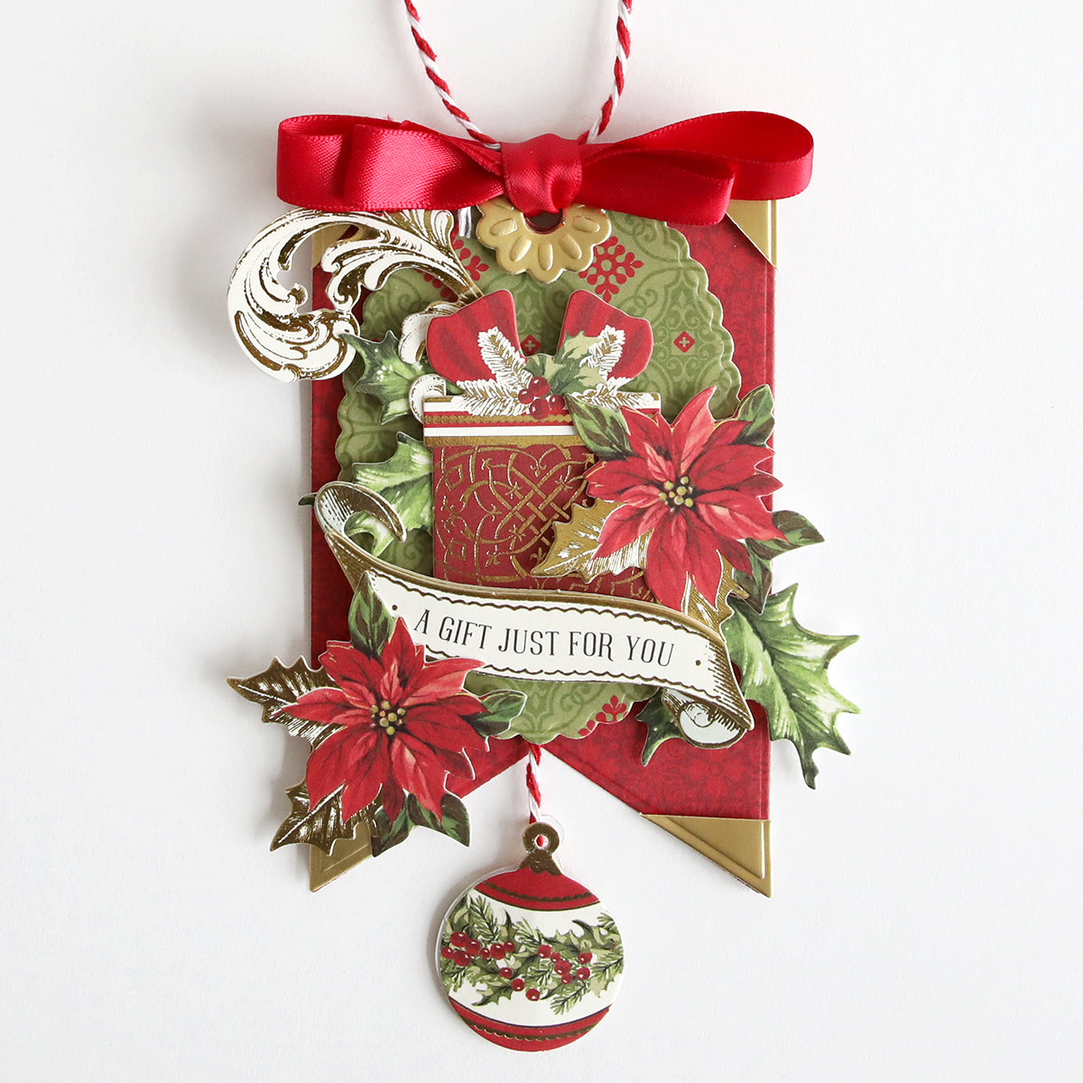 An Anna Griffin Gift Tag Compendium Class Materials and Dies custom tag with a handmade ribbon adorned with poinsettias.