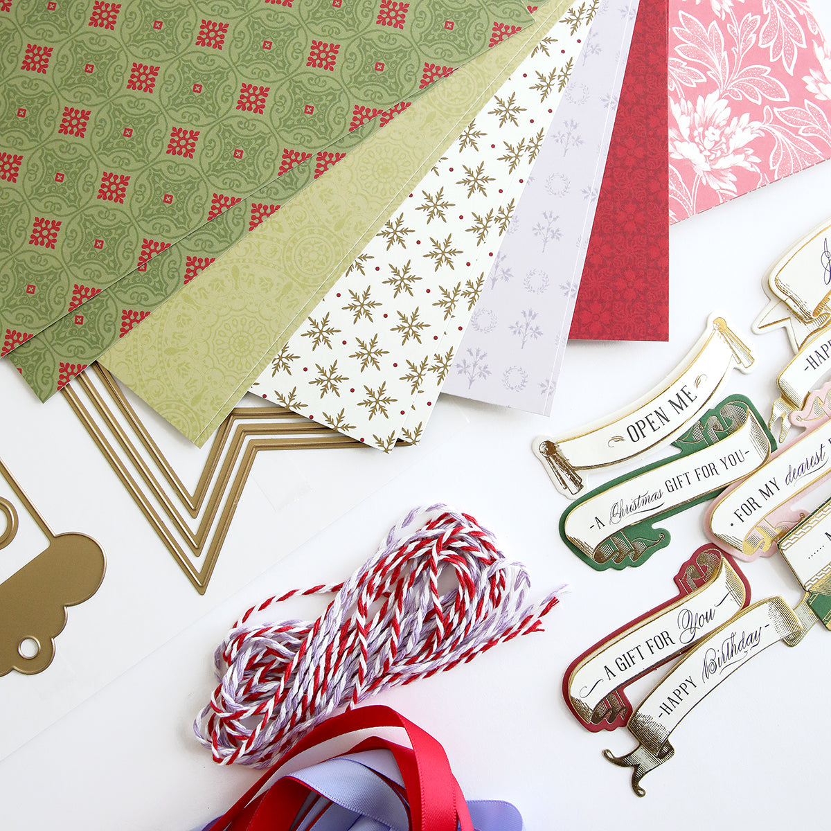 A variety of Anna Griffin Christmas gift papers and ribbons are laid out on a table.