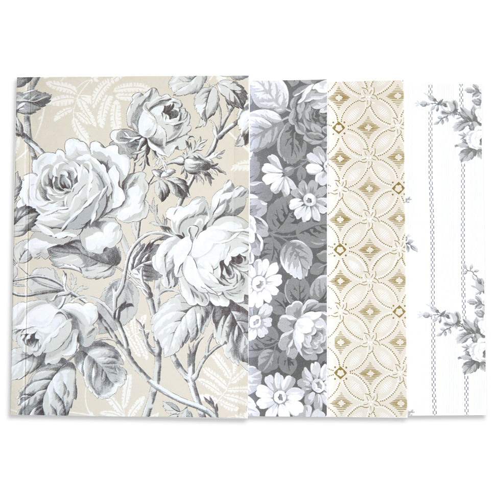 The Faded Rose Notebook Set features vintage floral and geometric patterns in beige, gray, and white with roses, daisies, ornate designs, and subtle shimmering gold foil accents.