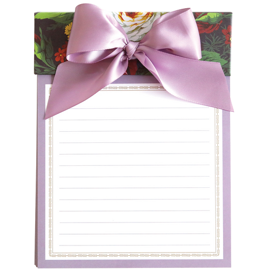 An elegant Astrid Floral Bow Pad gift box with a purple ribbon and a large notepad with lined and perforated sheets on top.