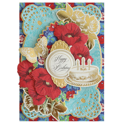 A stunning birthday card from the Hermosa Multi Cultural Cardstock collection, featuring vibrant red flowers, a golden butterfly, and a white cake with three candles. The design surrounds a "Happy Birthday" message set against a blue and red patterned backdrop. Ideal for members who appreciate beautiful designs inspired by Hispanic culture.