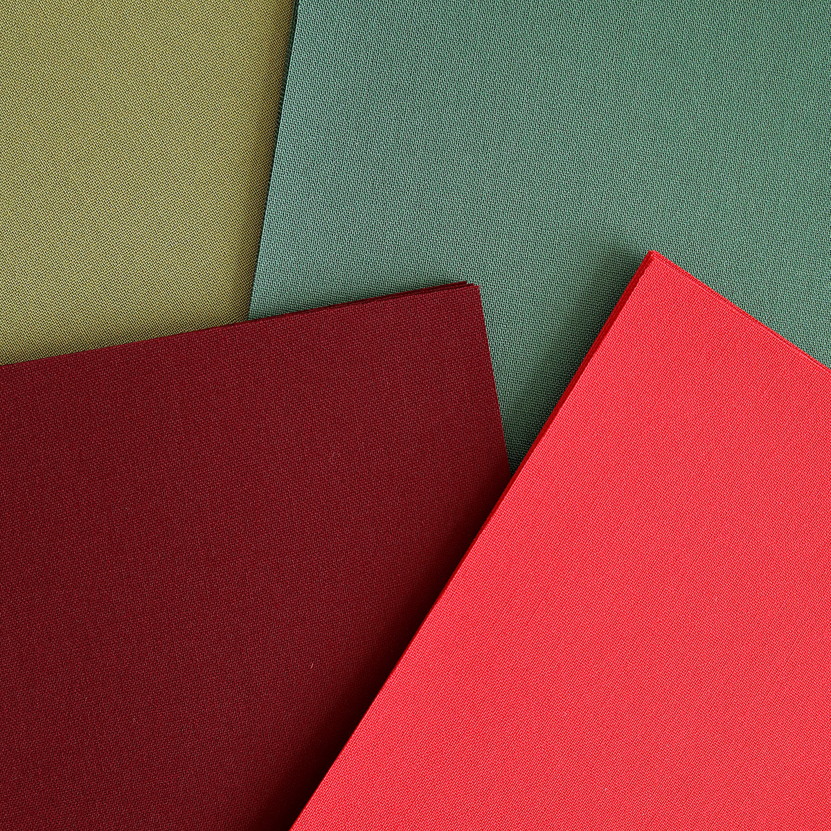 Four overlapping rectangular sheets from the Holiday Fabric Card Layers set—featuring olive green, forest green, burgundy, and red—are arranged in a slightly angled composition, perfect for adding a festive touch to your Christmas card projects.
