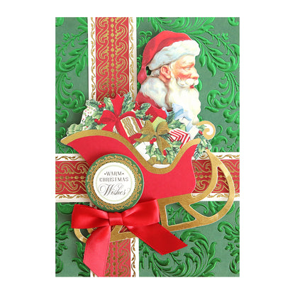 The Radiant Holiday Wreath and Bow Bundle features a holiday foil cardstock Christmas greeting card with Santa in a sleigh filled with gifts, a “Warm Christmas Wishes” tag, and a red ribbon bow.