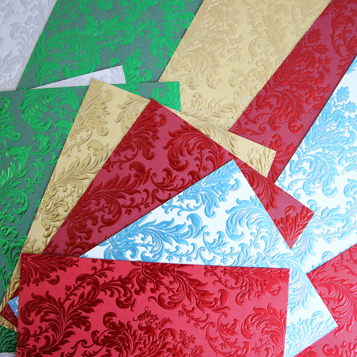 Luxury Holiday Tonal Foil Cardstock sheets in red, green, gold, and blue feature ornate floral embossing—ideal for card making or scrapbooking.