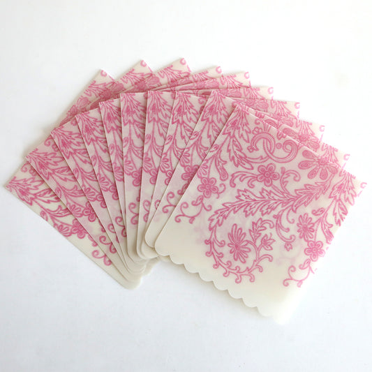 The Pink Lace Vellum Wrap 10 pack includes ten translucent bags, each featuring a pink floral lace pattern on a white background, perfect for elegant treat or invitation wrapping.
