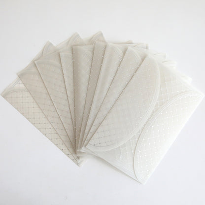 A 10-pack of Silver Foil Harlequin gatefolds with a translucent, patterned finish fanned out on a white surface, ideal for creating elegant wedding invitations.