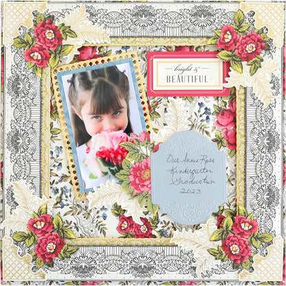A girl with bangs smelling pink roses, featured on a decorative scrapbook page with floral embossing and the text "beautiful" and "our little rose kindergarten graduate 2023.