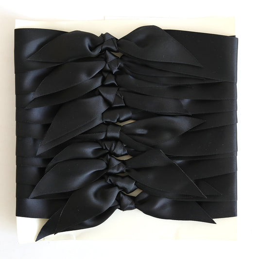 Ten pre-tied black satin knots are arranged in parallel rows on a white background—ideal for adding a stylish touch to handmade cards or crafts.