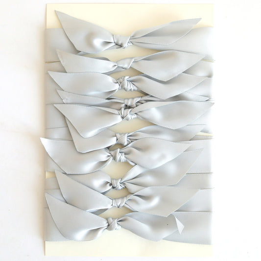 Ten pre-tied grey satin knots neatly arranged in two vertical columns on a cream rectangular background—ideal embellishments for handmade cards.