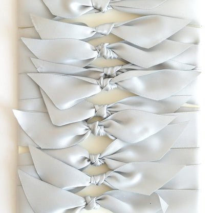 A row of Grey Satin Knots (10 count) is arranged on a white background—ideal for adding an elegant touch to handmade cards.