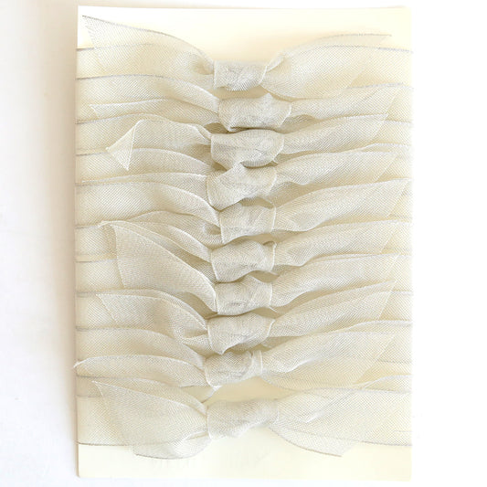Ten silver mesh knots, each 1" wide, are neatly arranged in two vertical columns on a rectangular cream-colored card.