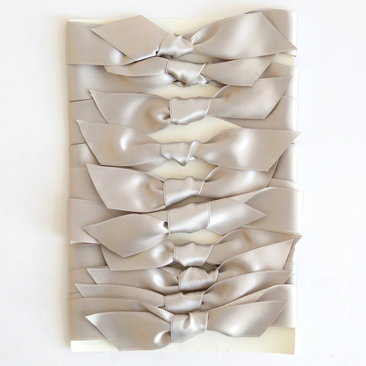 Ten silver satin knots are neatly arranged in two vertical columns on a white background, ideal for embellishing handmade cards or using as pre-tied ribbons.