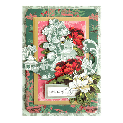 Layered papercraft card from the Lian Ultimate Papercrafting Collection with Rub On Transfers featuring a pagoda, red and white flowers, and a label reading “LIVE. LOVE. REJOICE.”