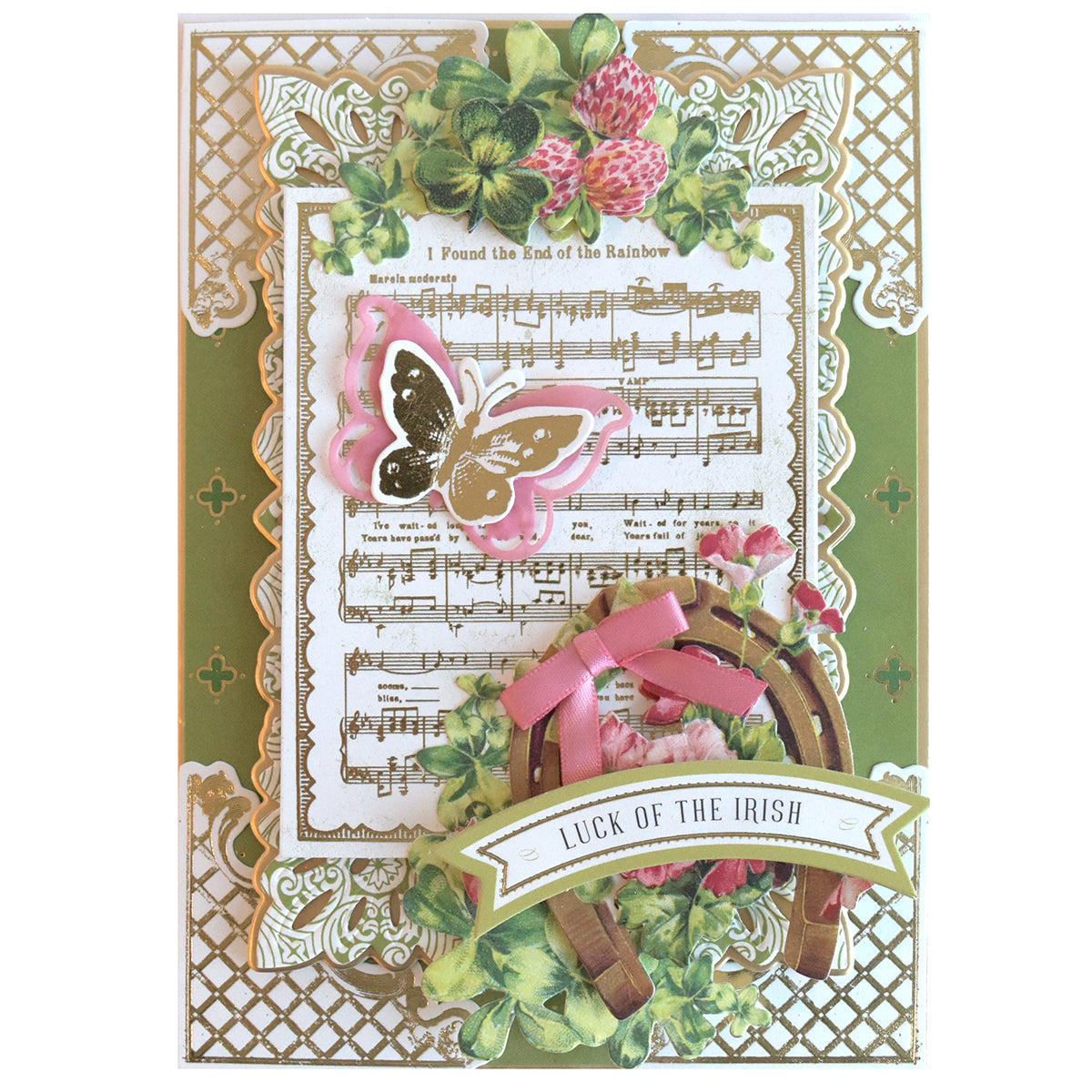Crafted with Lucky for All Double Sided Cardstock, this hand-made card features a gold lattice border, sheet music, a pink butterfly, clover leaves, horseshoe, pink bow, and a "Luck of the Irish" banner.