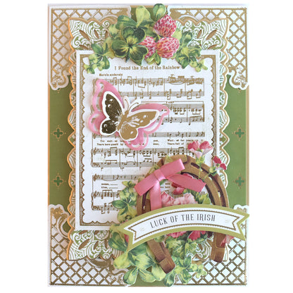 Crafted with Lucky for All Double Sided Cardstock, this hand-made card features a gold lattice border, sheet music, a pink butterfly, clover leaves, horseshoe, pink bow, and a "Luck of the Irish" banner.