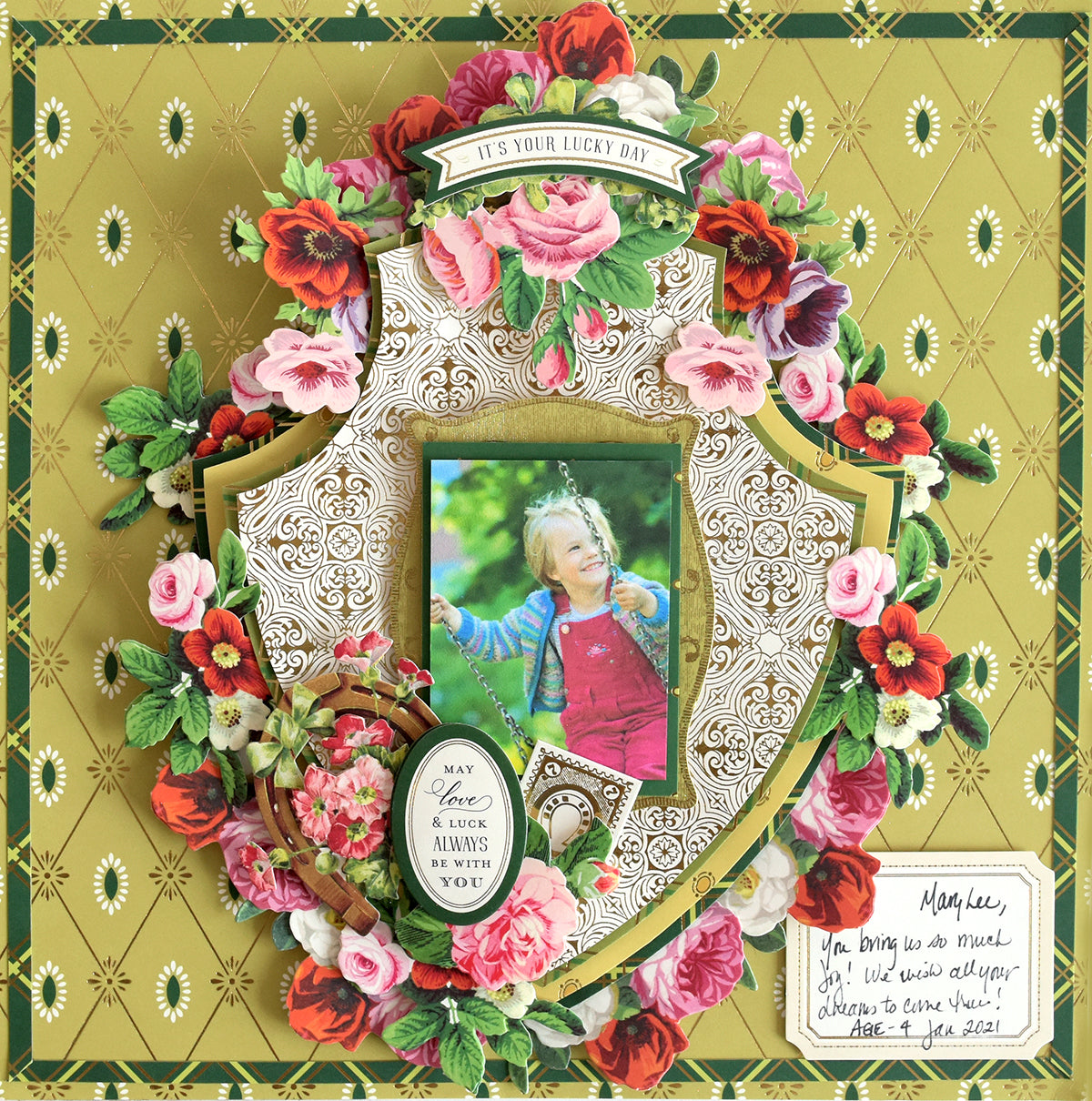 A decorative scrapbook page uses Lucky for All Double Sided Cardstock as the green patterned background, showcasing a smiling child, ornate floral designs, gold foil accents, a teapot cutout, and uplifting phrases.