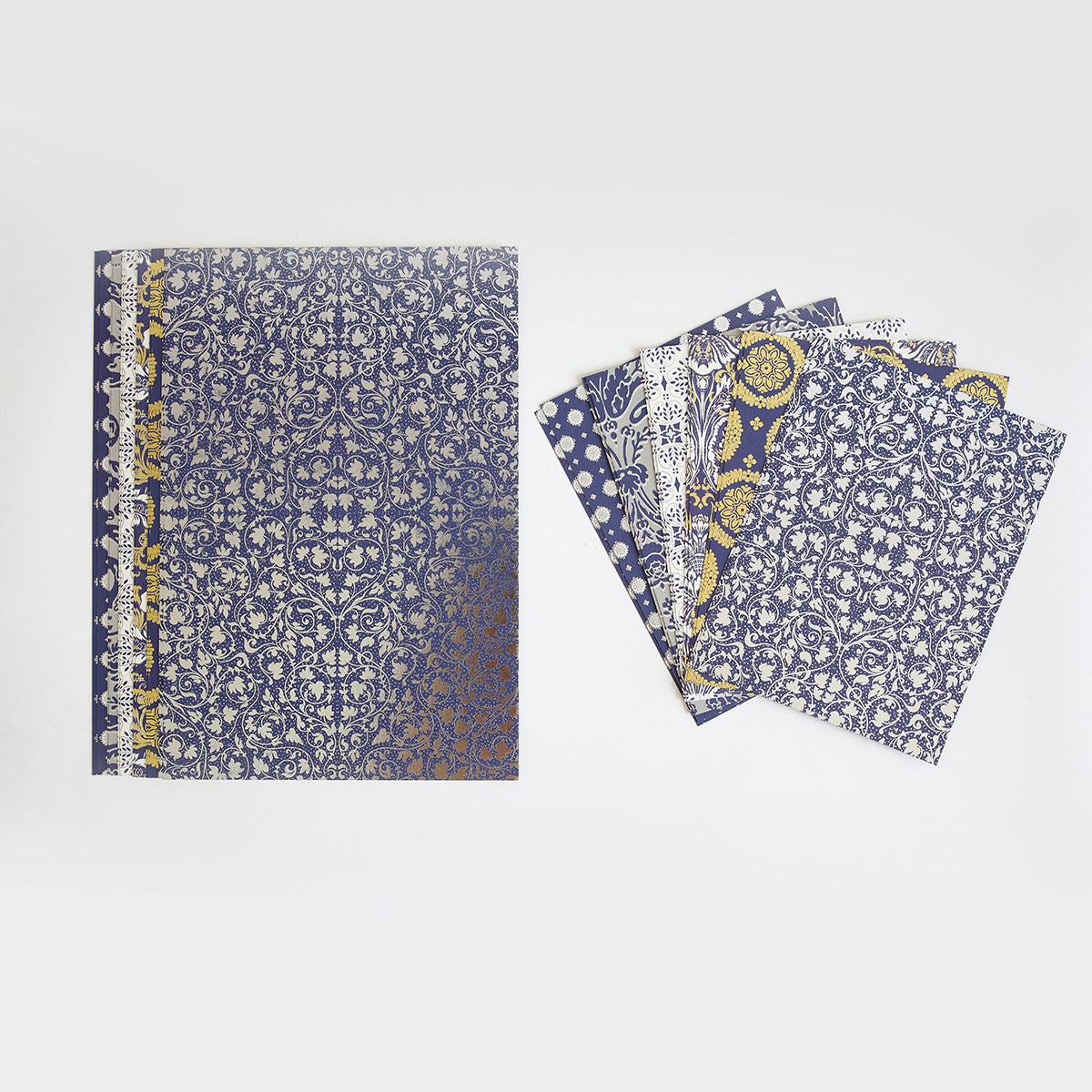 The Luxury Luster Foil Cardstock set includes a blue and gold patterned notebook beside five matching loose sheets with ornate designs, all displayed on a plain white background.