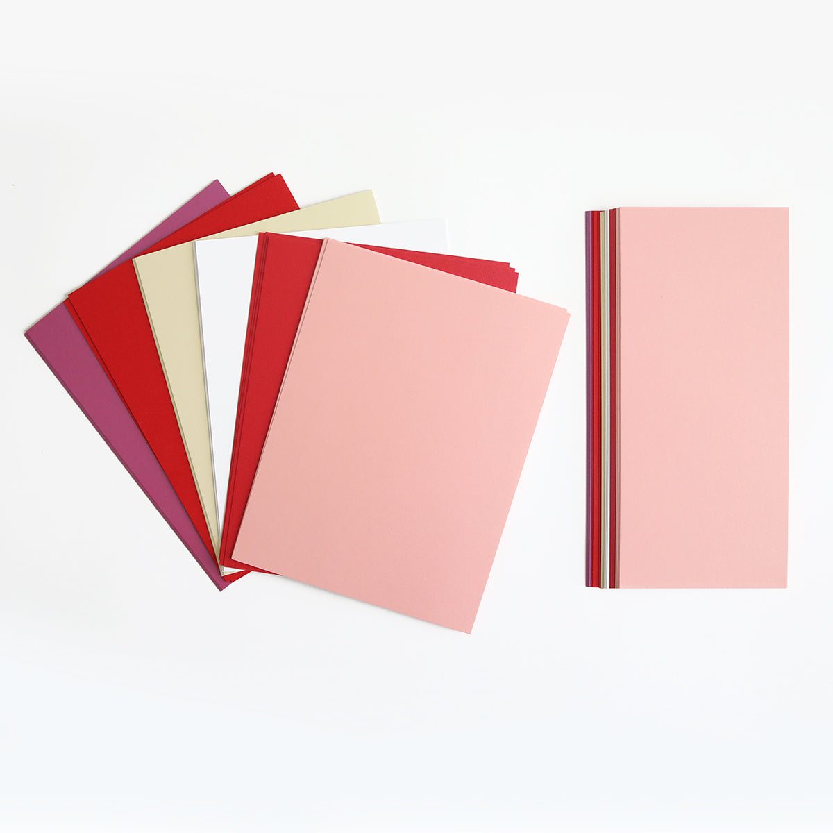 A set of Luxury Shimmer Cardstock - Lovely sheets in vibrant pink, red, beige, and purple hues. One stack is fanned out, while another is neatly piled on the right—ideal for embossing or creating exquisite handmade cards.