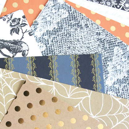 Mystery Halloween 12x12 Cardstock sheets overlap, showcasing patterns like gold polka dots, botanical designs, snakeskin textures, and geometric lines.