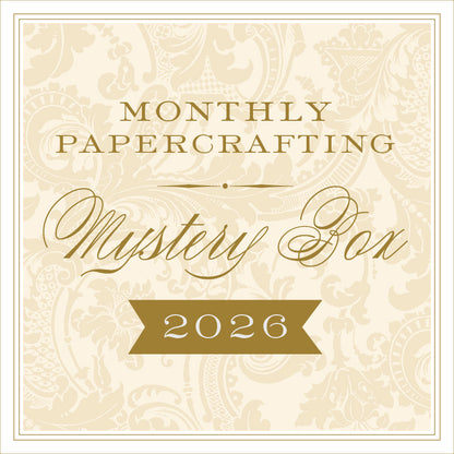 Beige and gold sign reading "Anna Griffin® 2026 Papercrafting Mystery Box Subscription" with a floral background—ideal for fans of the Anna Griffin Mystery Box or those looking for unique card making supplies.
