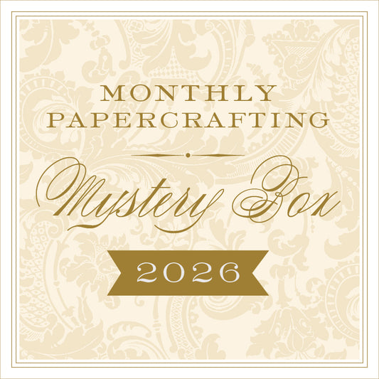 Beige and gold sign reading "Anna Griffin® 2026 Papercrafting Mystery Box Subscription" with a floral background—ideal for fans of the Anna Griffin Mystery Box or those looking for unique card making supplies.