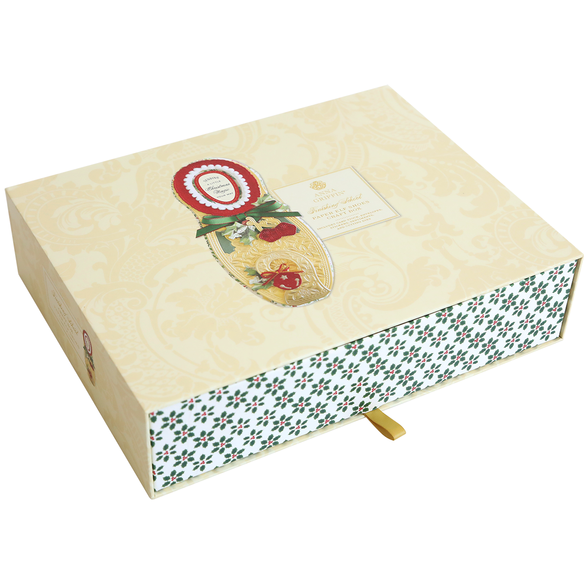 The Paper Elf Shoe Finishing School Craft Box is a decorative, beige craft box with a festive design. It features a gold patterned lid adorned with holly and a red seal, along with a lower portion that boasts a green and white pattern reminiscent of elf shoes. Additionally, it has an attached gold ribbon tab.