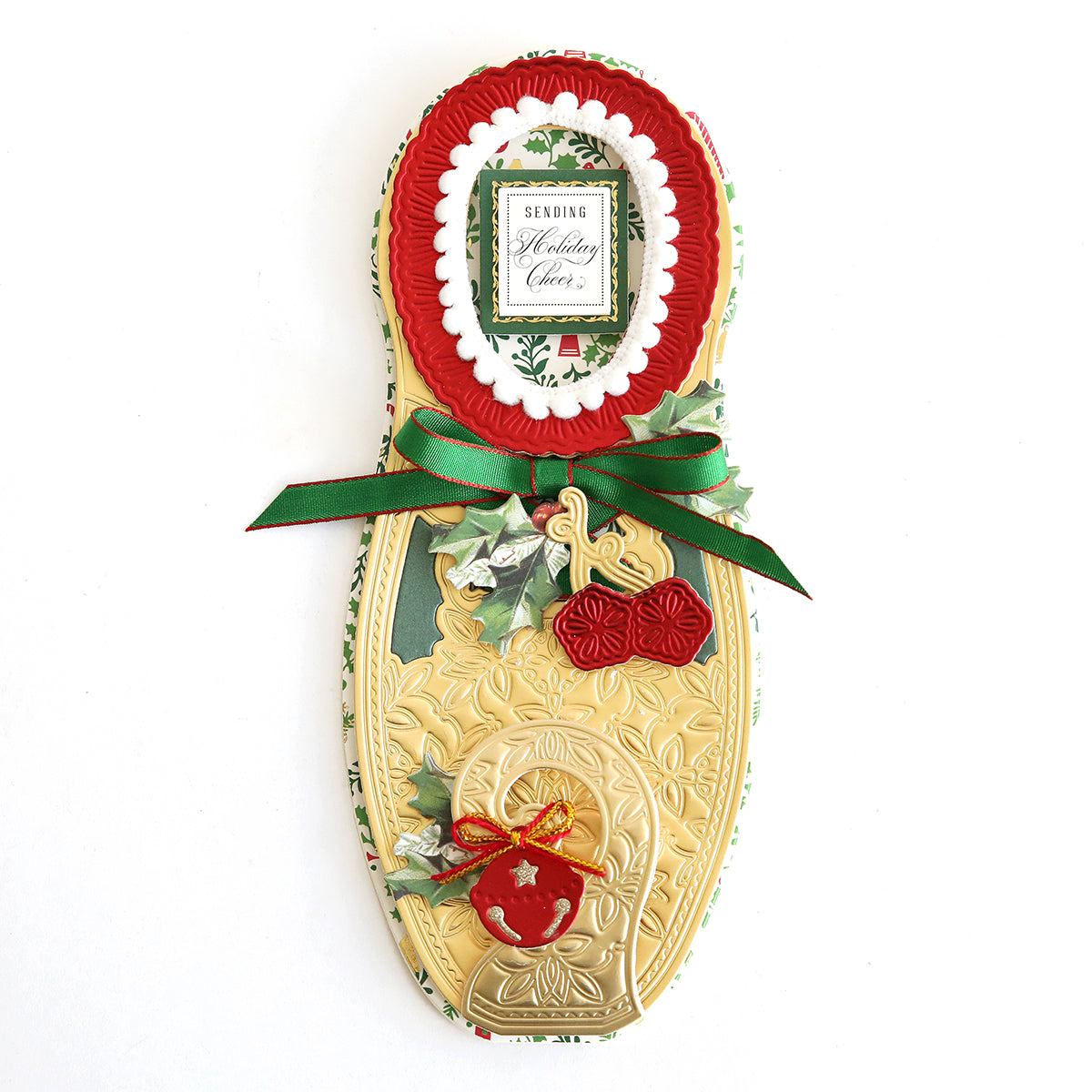 A festive card shaped like an elf shoe, crafted from high-quality cardstock and adorned with green ribbon, holly leaves, and an ornament. Featuring delightful embellishments and a tag that reads "Sending Holiday Cheer," the Paper Elf Shoe Finishing School Refill Kit is perfect for spreading holiday joy.