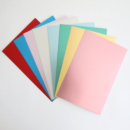 A fanned arrangement of colored paper sheets, including red, blue, green, white, yellow, and pink Phoebe Luxury Matte Foil Cardstock 8x12 from Phoebe Design, is displayed against a white background.