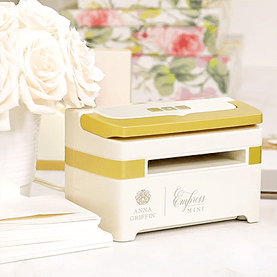 An exclusive AG Membership gold and white machine sits on a table next to a bouquet of flowers.
