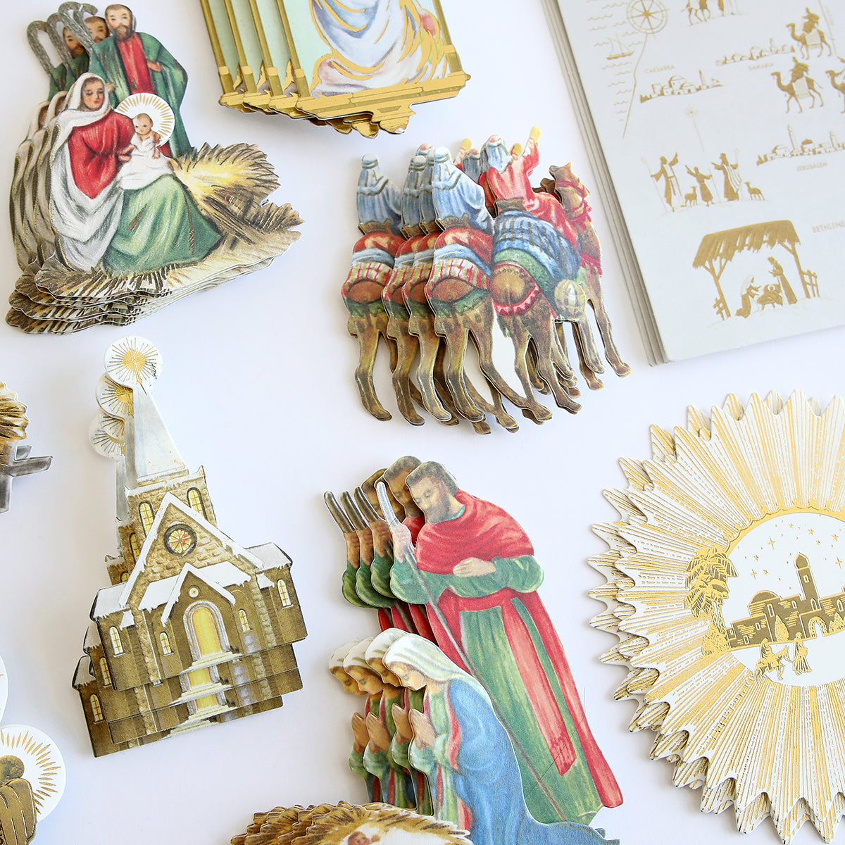 An assortment of colorful, vintage-style Reason for the Season Embellishments featuring nativity scenes, religious figures, camels, a church, and decorative elements on a white background. Perfect for adorning Christmas cards or enhancing storage folios with a festive touch.