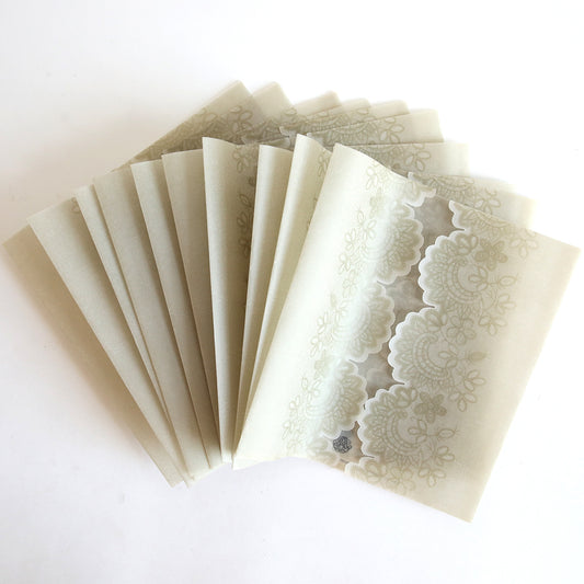 The Platinum Vellum Lace Gatefold 10 pack features translucent envelopes with an elegant lace pattern, ideal for wedding invitations or gatefold designs, displayed fanned out on a white surface.