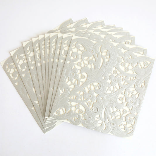 The Silver Embossed Lace Gatefold 10 pack features cream-colored, square wedding invitations with intricate laser-cut floral and swirl patterns, evoking embossed lace details and a subtle silver shimmer for an elegant celebration.