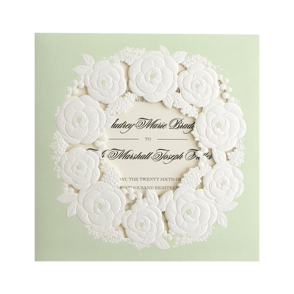 A wedding invitation with white flowers on a green background.