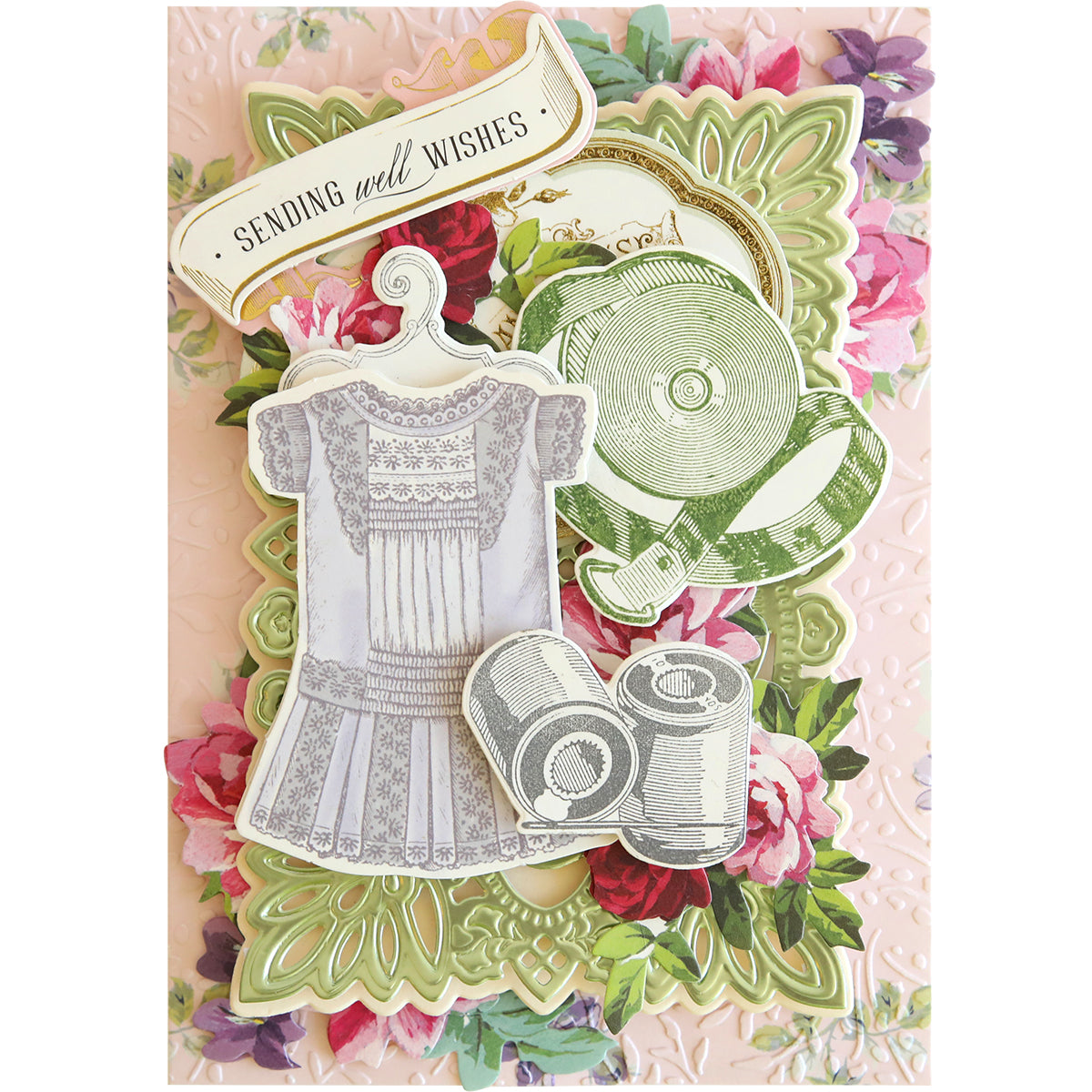 A handmade card created with Sewing Stamps and Dies, showcasing die cut tags, floral patterns, a lacy dress illustration, a music record, and the message "Sending well wishes.