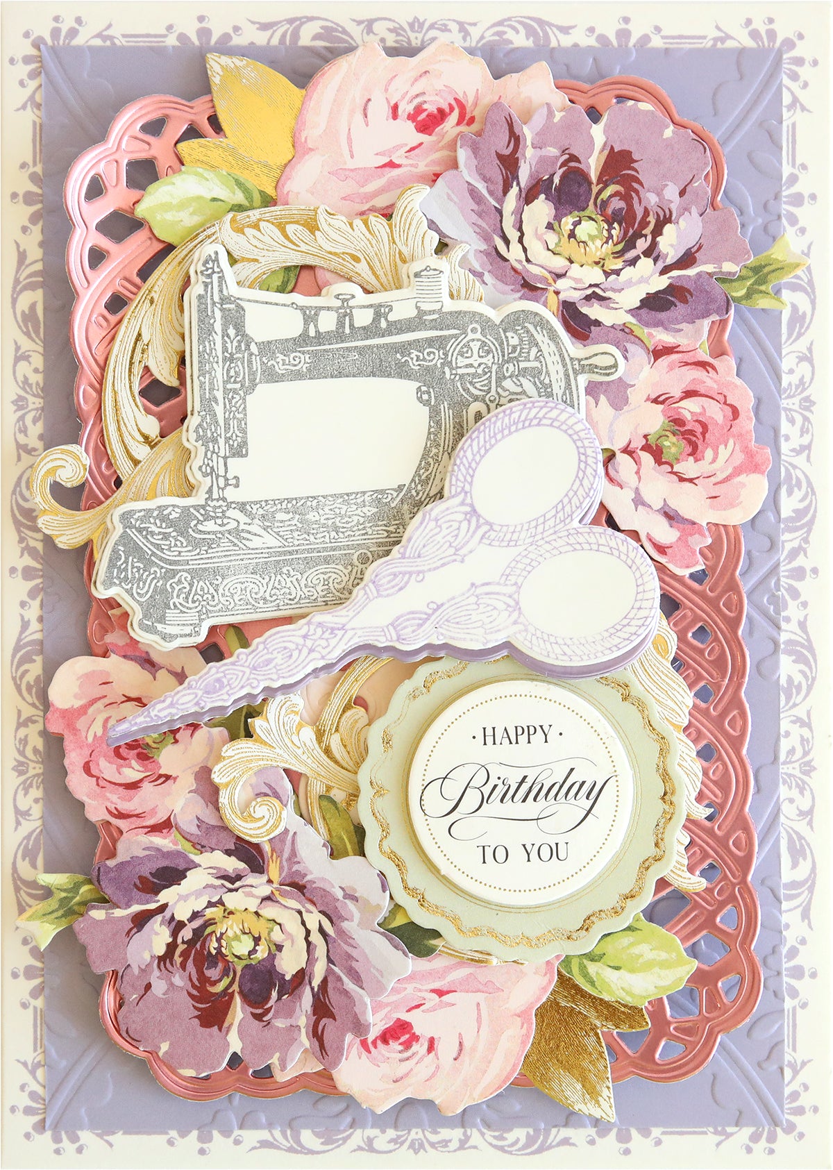 A decorative birthday card featuring an intricate design with flowers, a vintage sewing machine illustration, scissors, die cut tags, and a "Happy Birthday To You" message crafted using the Sewing Stamps and Dies set.