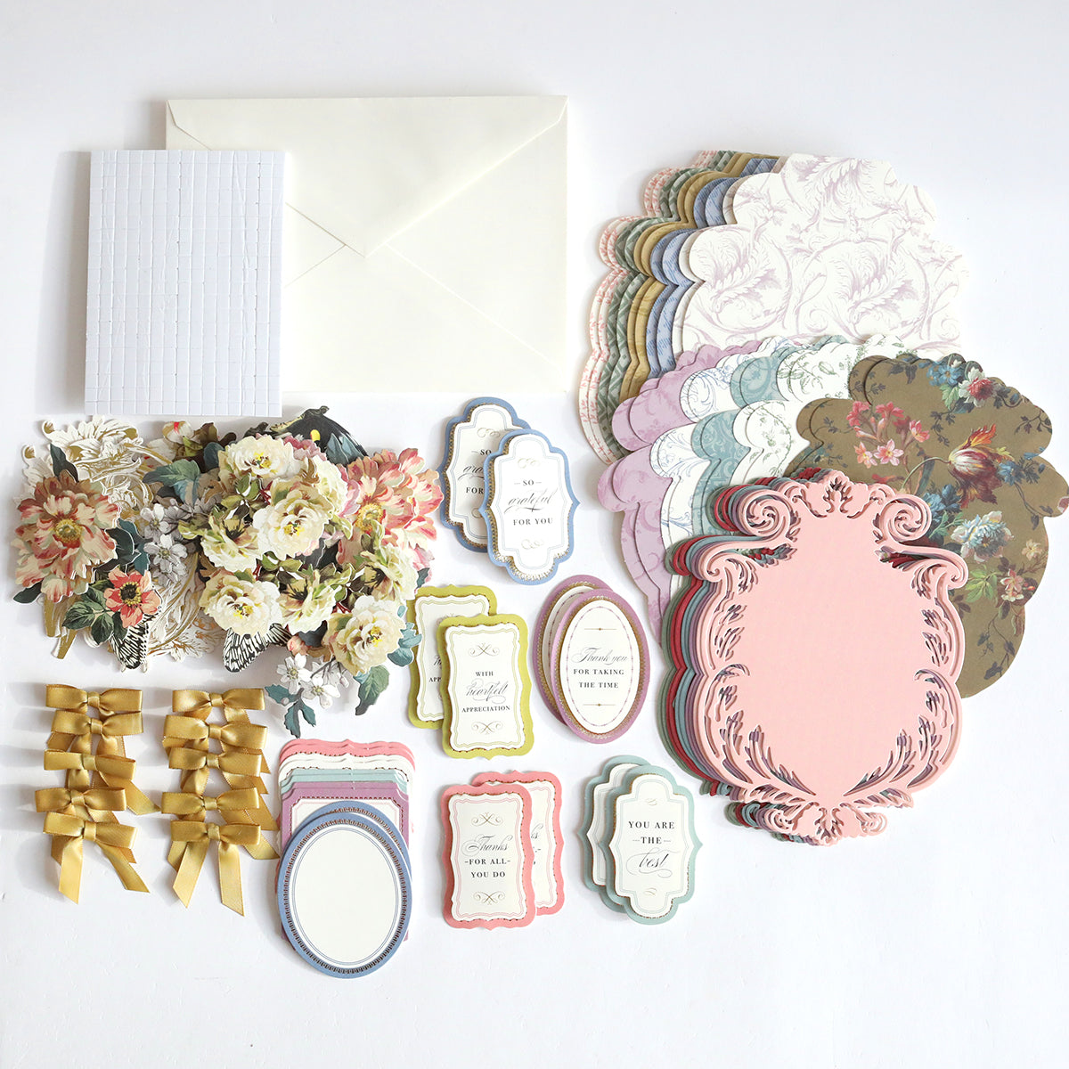 A collection of crafting supplies, including the Simply Appreciation Easel Card Making Kit, floral cutouts, golden ribbons, and an envelope arranged on a white surface.