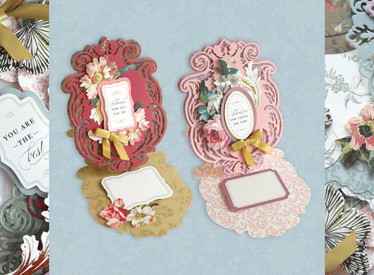 Two ornate greeting cards with floral designs and attached yellow ribbons. The left card is red, and the right card is pink. Both cards have blank spaces for personalized messages.