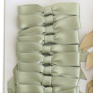 Eight Small Pre-Tied Bows in sage green are neatly arranged in a vertical row on a white surface.