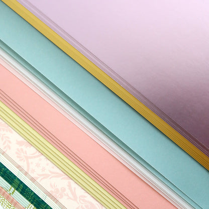 The Crop at Home 5 Swag Materials feature stacks of pastel-colored and patterned premium papers arranged in overlapping layers—perfect for your next crafting project.